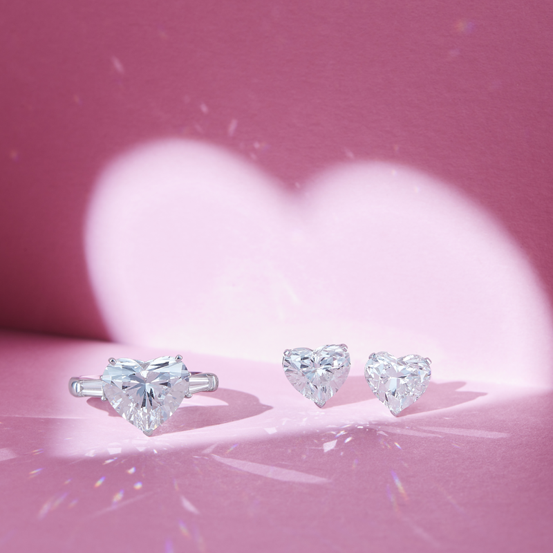 На фото: кольцо Mercury Classic из белого золота с центральным бриллиантом огранки сердце и двумя бриллиантами огранки багет, серьги с бриллиантами огранки сердце